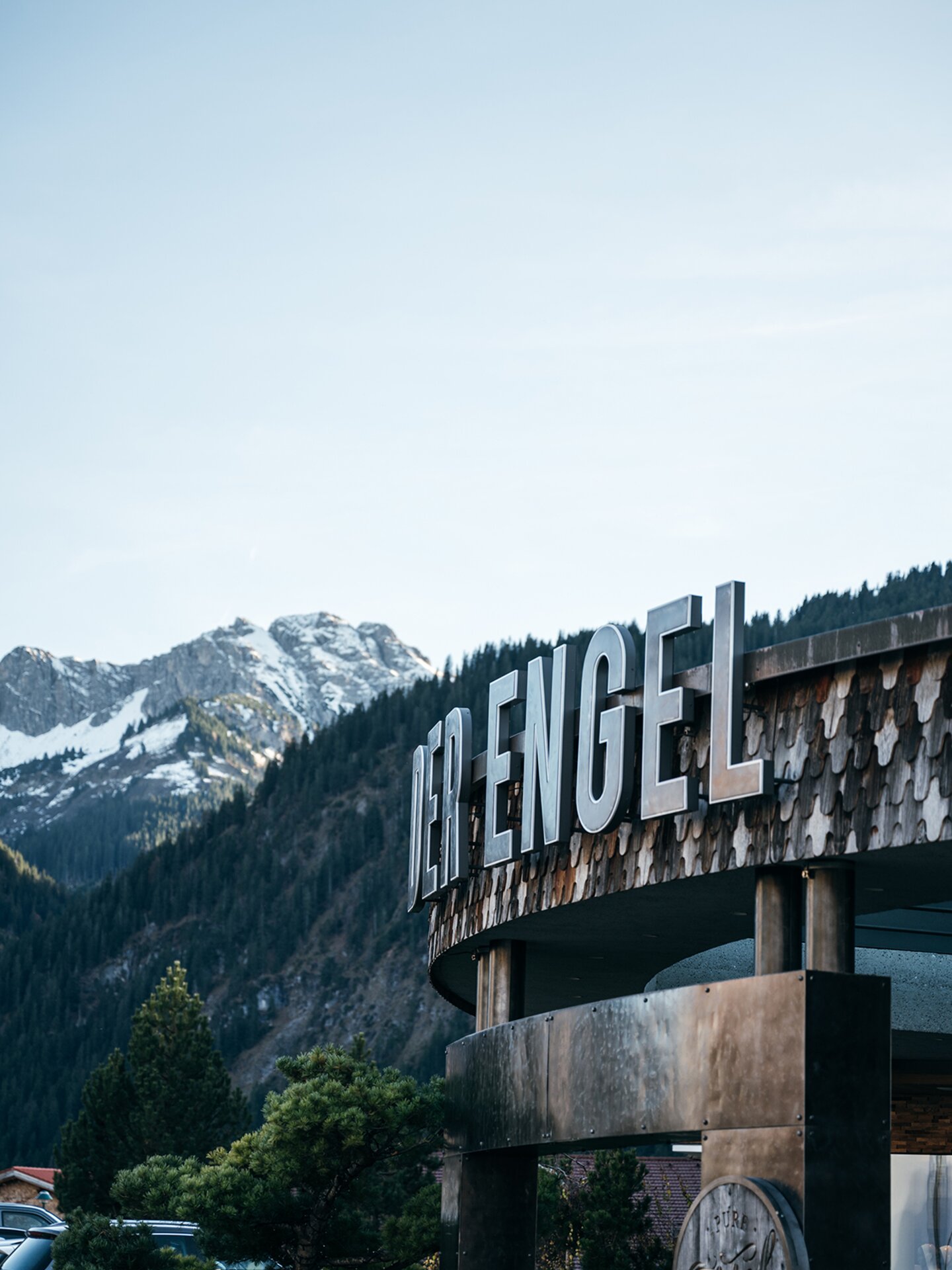 Hotel Der Engel Schriftzug am Dach mit Holzschindeln und im Hintergrund die Allgäuer Alpen | Der Engel in Tirol