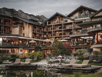 Hotel Der Engel with a mountain lake in the foreground at dusk, exterior view