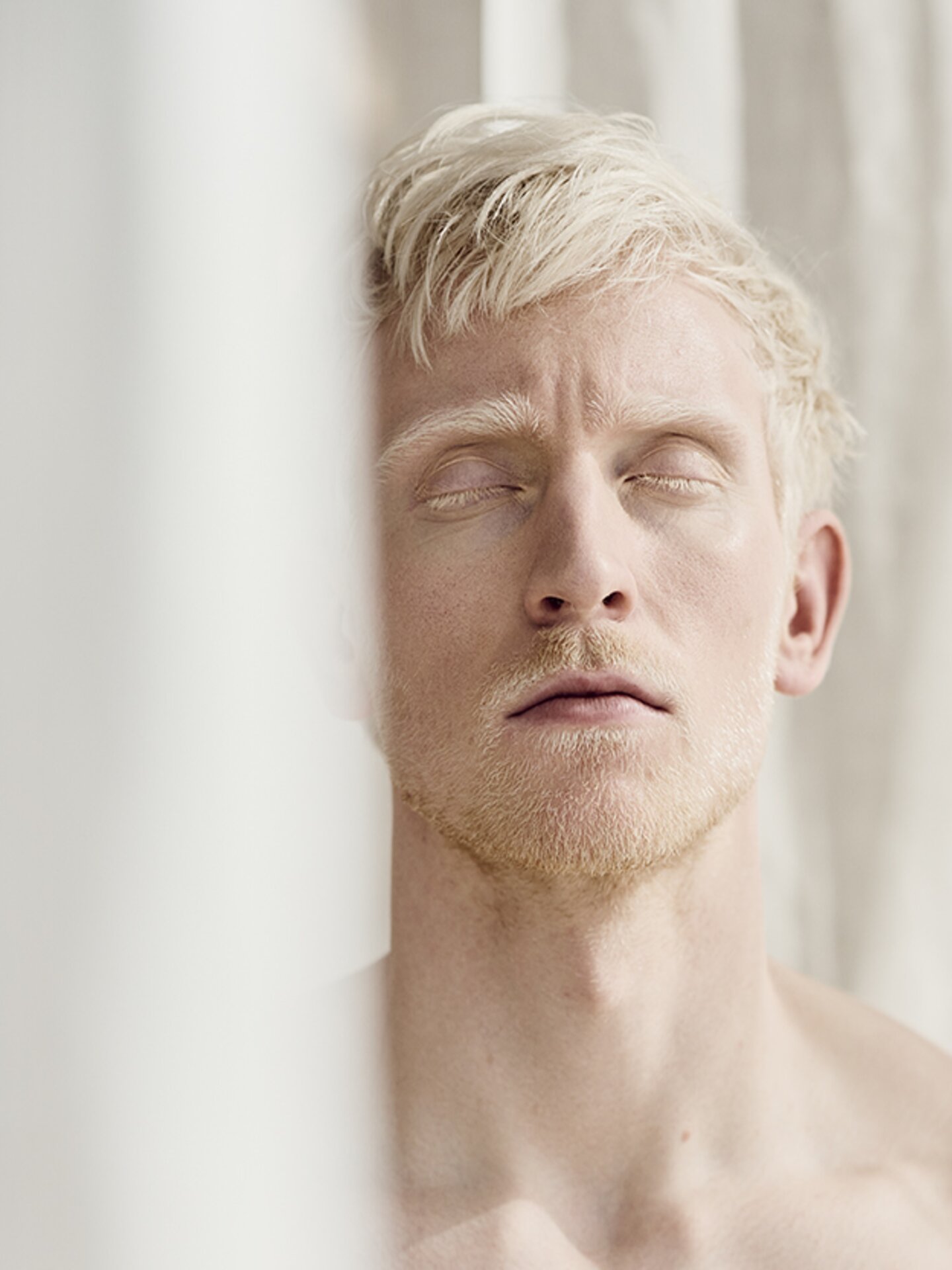 Person beim Meditieren hinter einem weißen Vorhang. Weiß auf Weiß