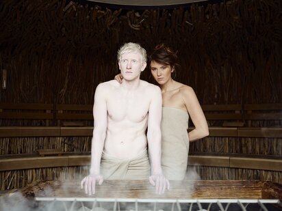 Zwei Personen vor Sauna Ofen beim Aufguss in der Event Sauna mit Treibholzdecke | Der Engel in Tirol