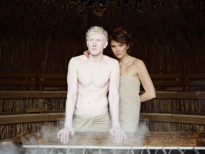 Zwei Personen vor Sauna Ofen beim Aufguss in der Event Sauna mit Treibholzdecke | Der Engel in Tirol