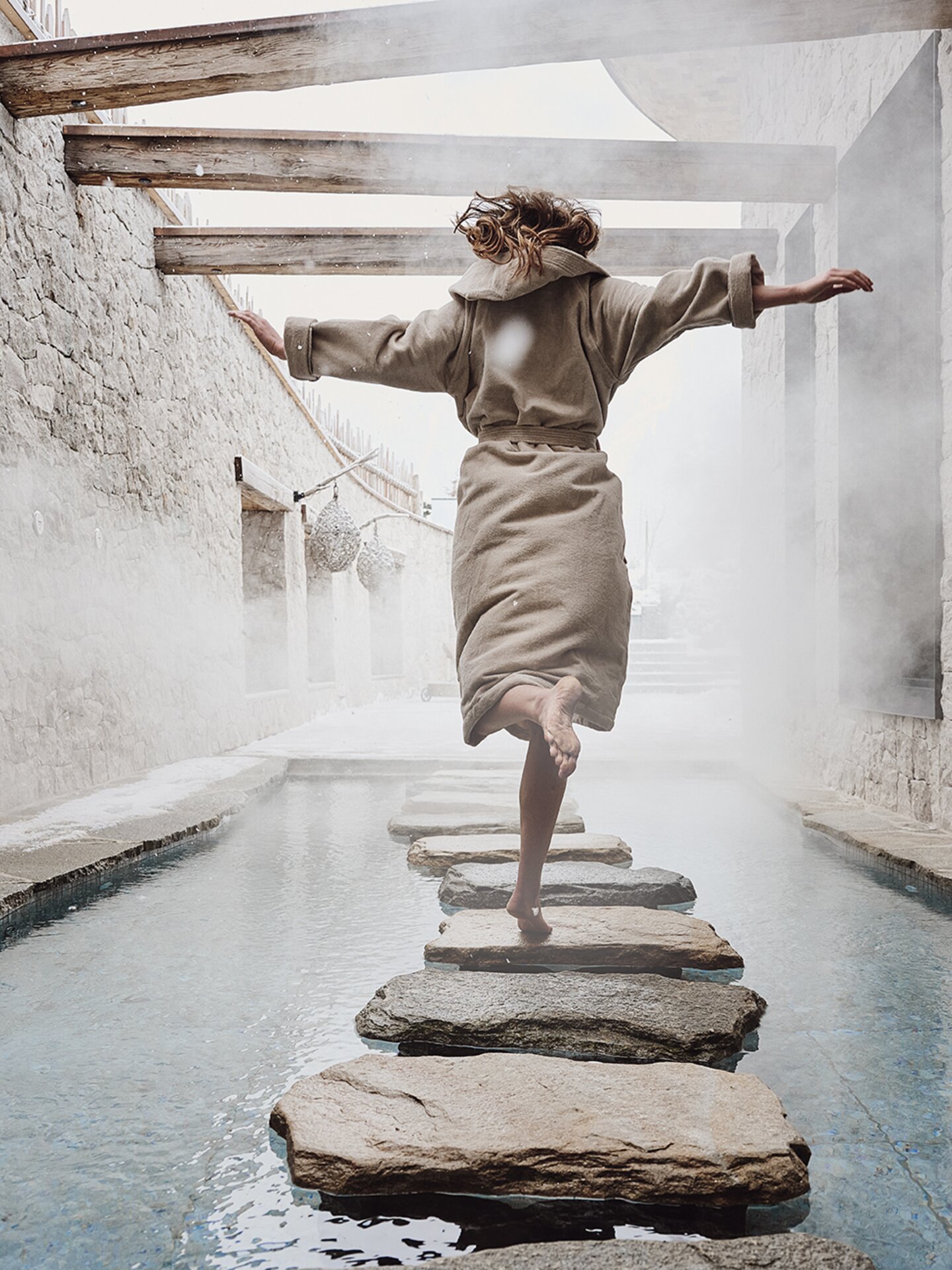 Person springt auf Steinpfad im Kneippbecken | Der Engel in Tirol