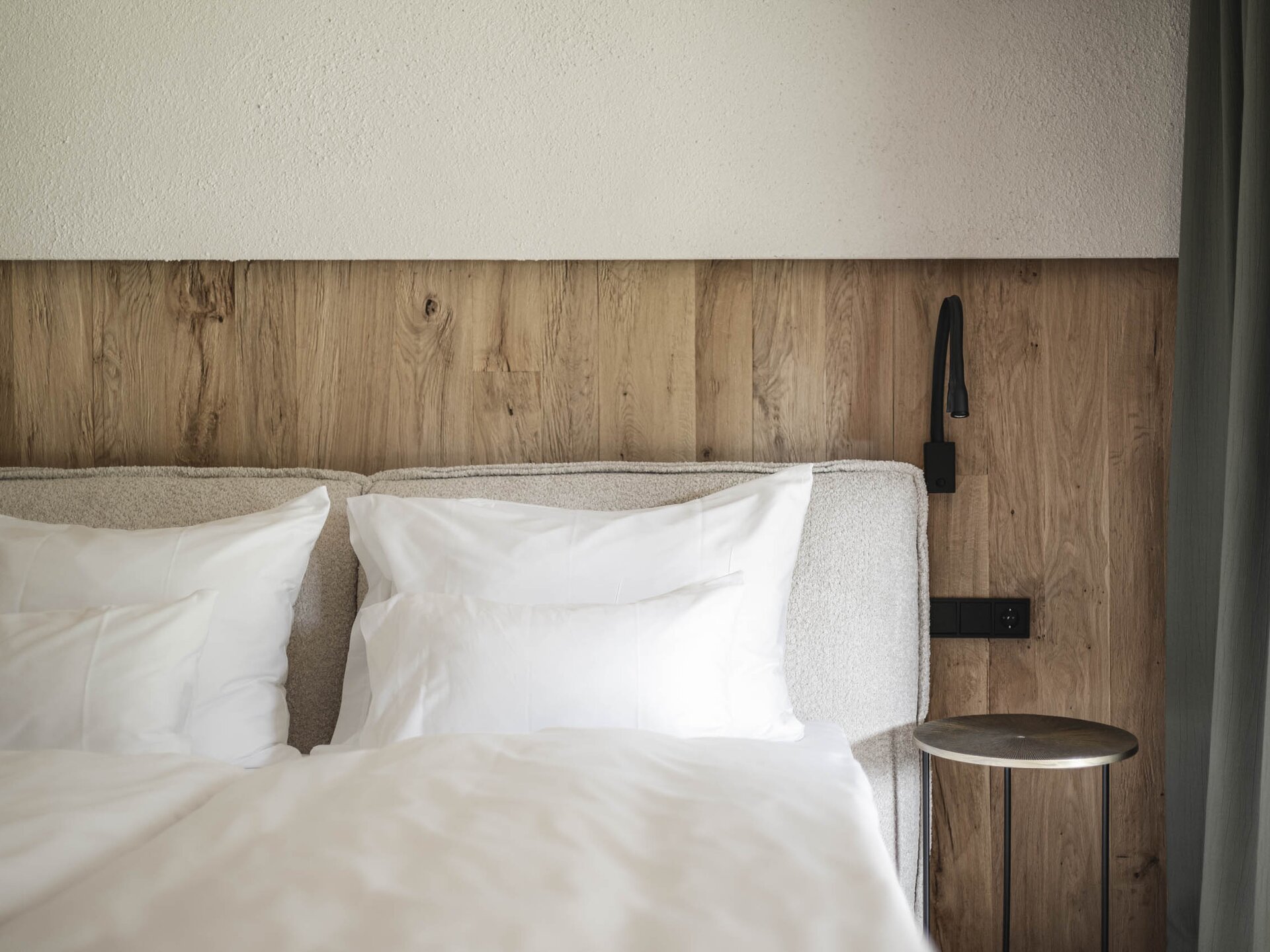 Nahaufnahme des Bettes und der Nachttischleuchte mit Vorhang in der Krautgarten Suite