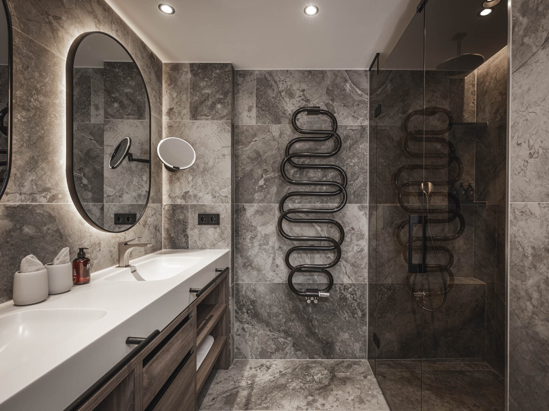 In grau gefliestes Badezimmer mit schwarzen Armaturen und Doppelwaschtisch und Dusche in den Suites am Krautgarten