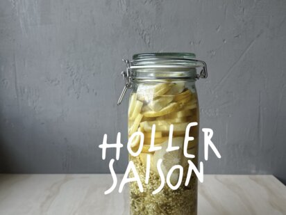 Glas mit Zitronenscheiben und Hollerblüten für hausgemachten Sirup