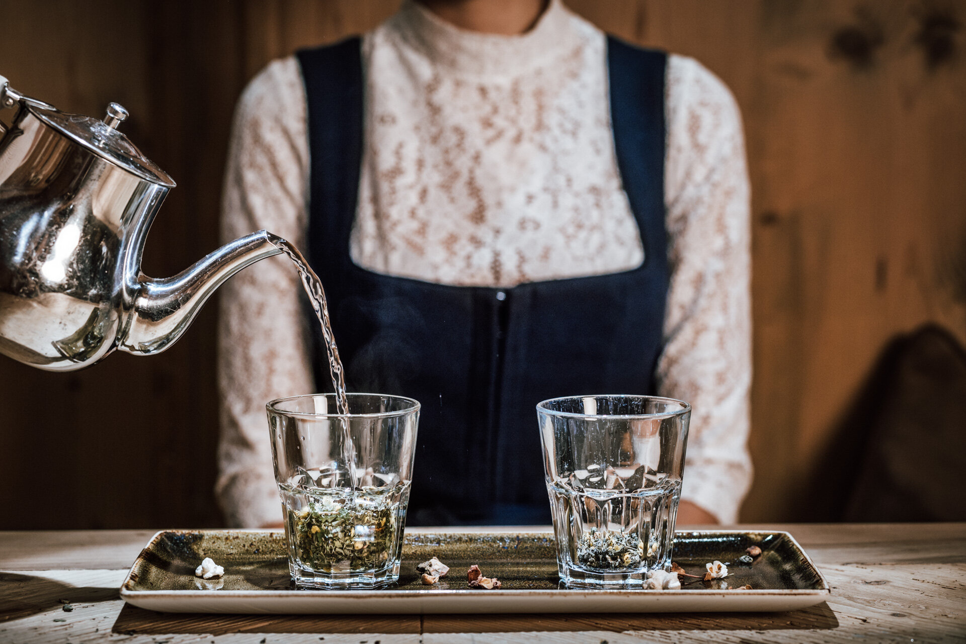 Tee eingießen in Glas im Hintergrund Person mit traditionellem Tiroler Dirndl | Der Engel in Tirol
