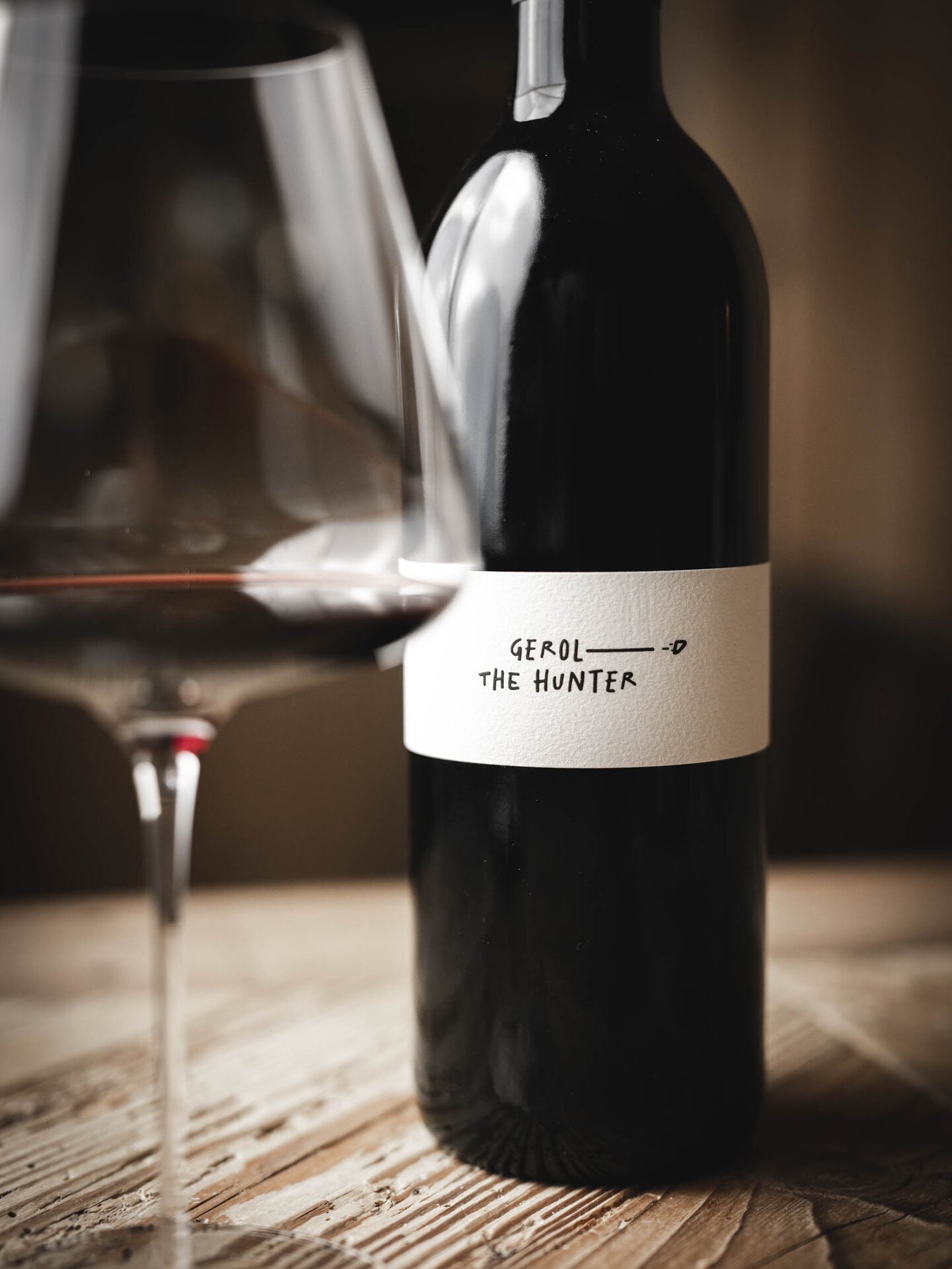 Elegantes Weinglas und Rotwein-Flasche Gerold the Hunter auf Holztisch