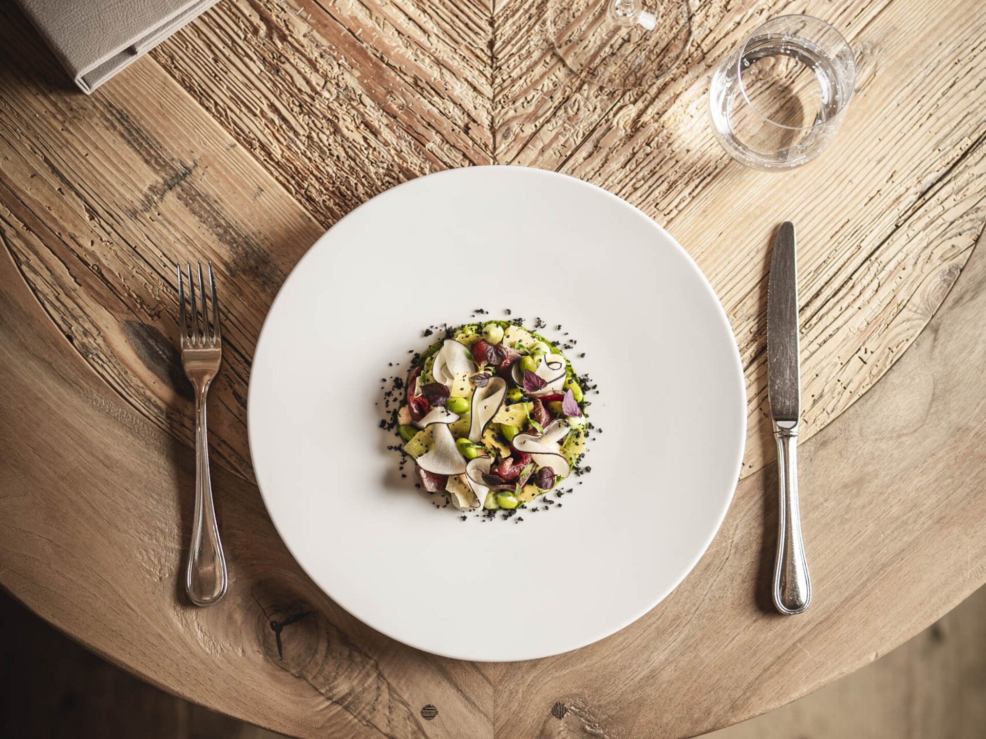 Gericht von Lukas Rettenbacher auf weißem Teller und Holztisch | Gut essen im Tannheimer Tal
