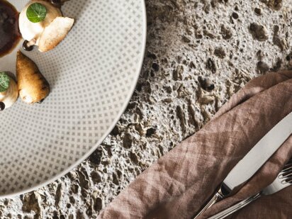 Teller mit traditionellem Mittagsgericht steht auf einem Steinuntergrund und eine Flasche Wein daneben