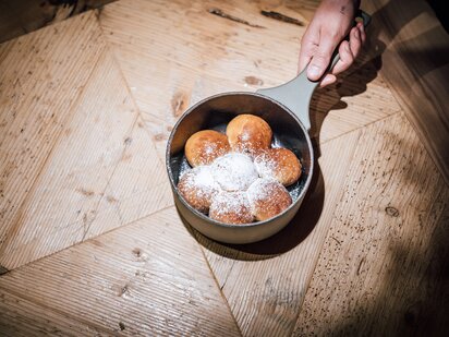 Traditionelle Tiroler Mehlspeise Buchteln in Eisenpfanne auf Holztisch | Der Engel in Tirol