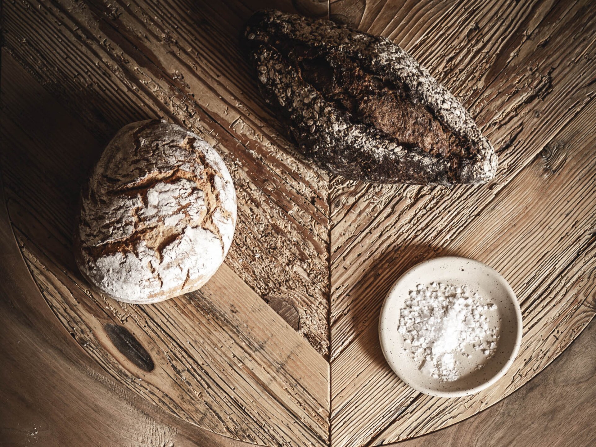 Frisch gebackenes, handgemachtes Brot auf einem alten Holztisch - am Anfang war das Brot, dann kam alvä