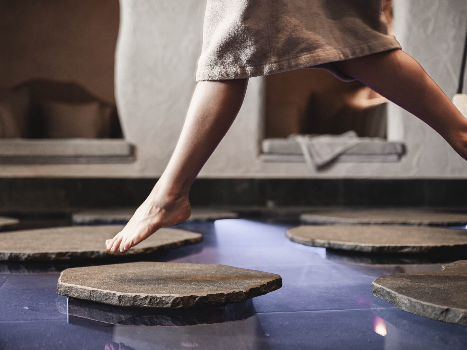 Person springt von Stein zu Stein im Biotop | Wellness-Winterurlaub im Tannheimer Tal