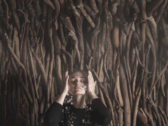 Gast sitzt mit Skiunterwäsche in Sauna und kühlt sich mit Crushed Ice im Gesicht