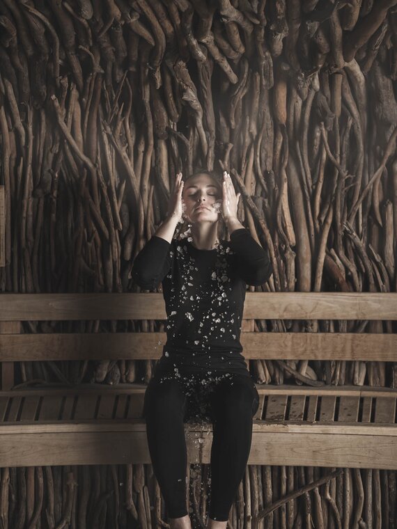 Gast sitzt mit Skiunterwäsche in Sauna und kühlt sich mit Crushed Ice im Gesicht