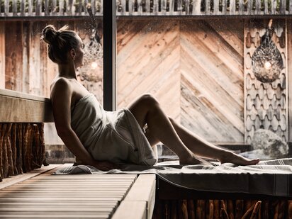 Person liegt mit Handtuch umwickelt in der Eventsauna des Orgänic Spa