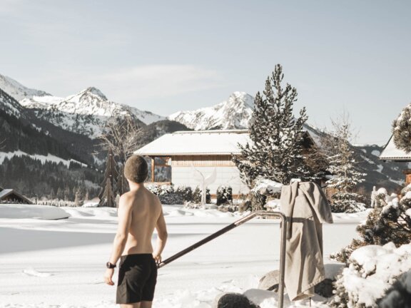 Person beim Eisbaden im Engel Bergsee, die Landschaft schneebedeckt
