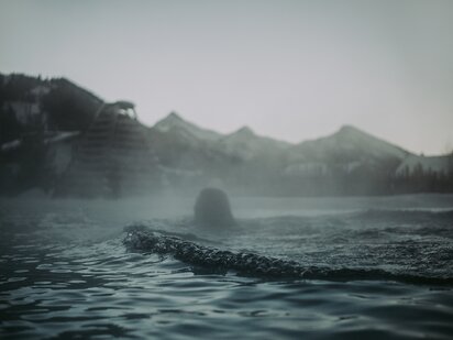 Schwimmer im Außenpool mit Wasserdampf im Winter | Der Engel in Tirol