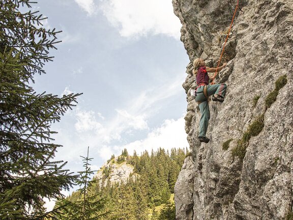 Person beim Klettern in Felswand im Tannheimer Tal Person beim Klettern in Felswand im Tannheimer Tal
