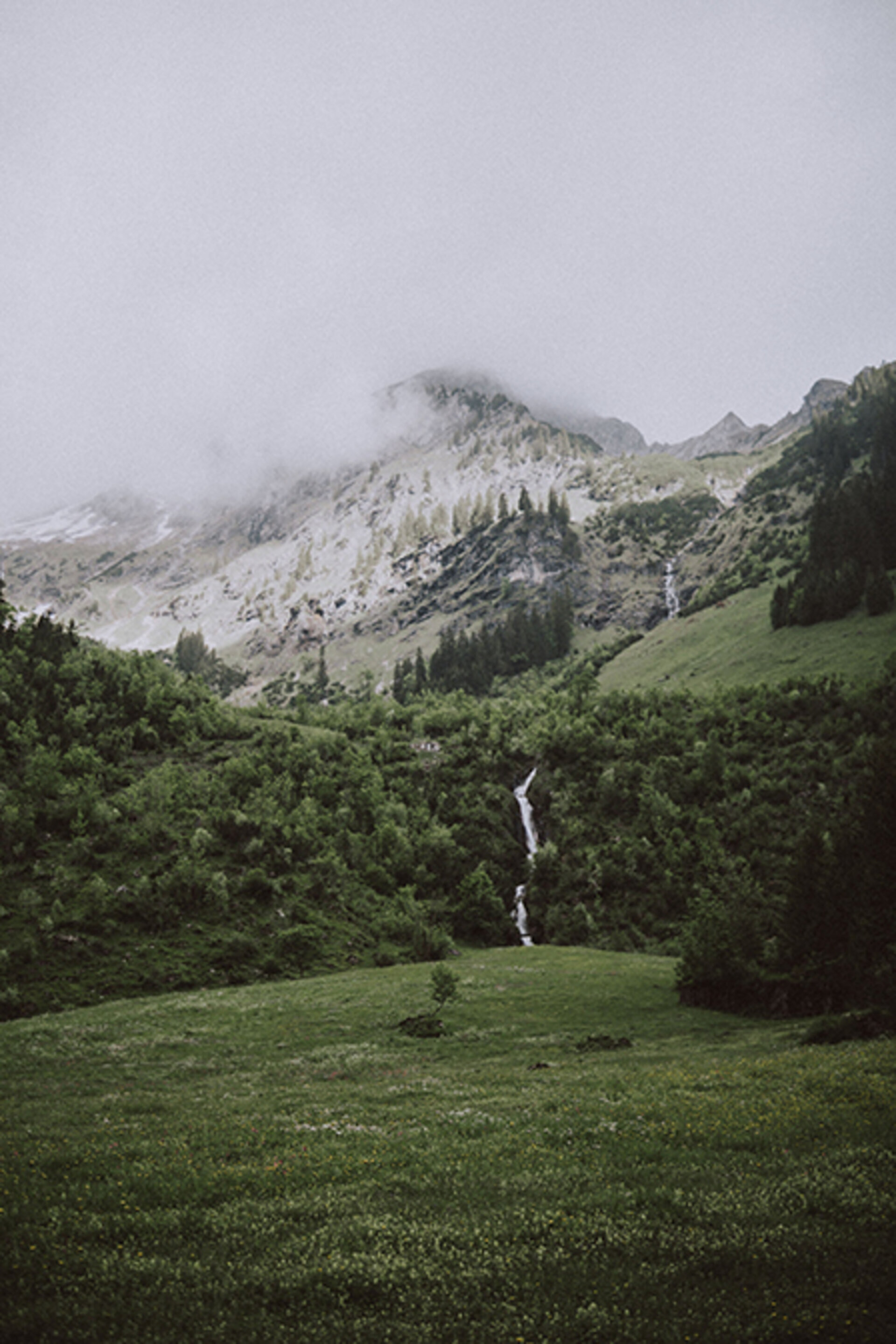 Kleiner Wasserfall zwischen saftig grünen Wiesen mit Nebel | Der Engel in Tirol