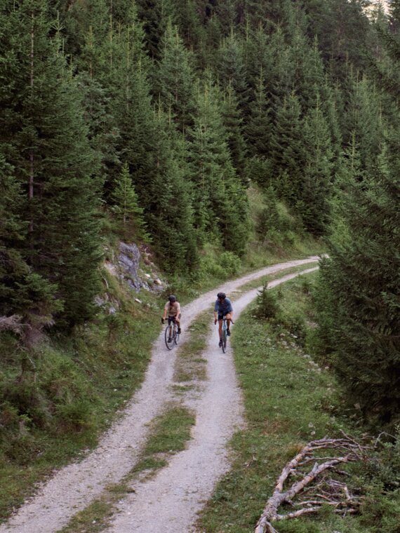 Zwei Mountainbiker auf einem Forst-Radweg im Wald im Tannheimer Tal