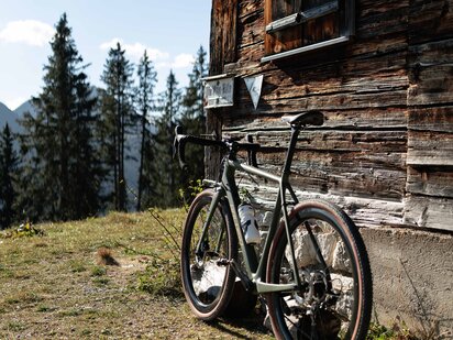 Gravelbike vor alter Holzhütte am Berg im Tannheimer Tal