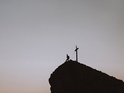 Person auf dem Gipfel des Aggenstein in der Dämmerung kurz vor dem Sonnenuntergang