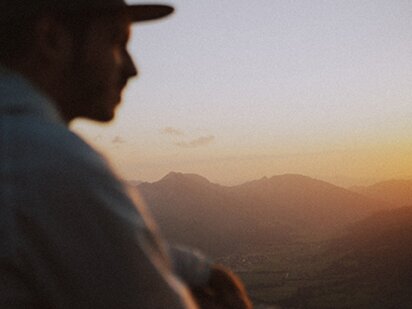 Person in Nahaufnahme am Gipfel in den Allgäuer Alpen im Tannheimer Tal beim Sonnenuntergang