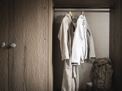 Orgänic Zimmer mit Wanderjacke und Bademantel im Kleiderschrank sowie Wanderrucksack