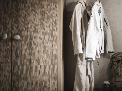 Orgänic Zimmer mit Wanderjacke und Bademantel im Kleiderschrank sowie Wanderrucksack