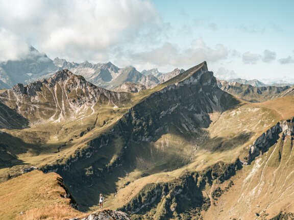 Person beim Wandern steht am Rand zum Abgrund am Weg zur Schochenspitze im Tannheimer Tal