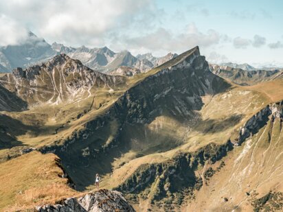 Person beim Wandern steht am Rand zum Abgrund am Weg zur Schochenspitze im Tannheimer Tal