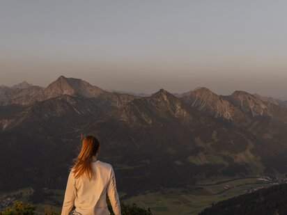 Person in Sportklamotten beim Sonnenaufgang im Sommer am Aggenstein im Tannheimer Tal
