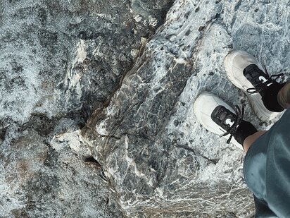 Person in Vogelperspektive steht mit Trail Running Schuhen im Sommer auf einem Felsen