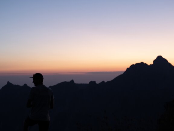 Silhouette einer Person vor den Bergen bei Sonnenaufgang