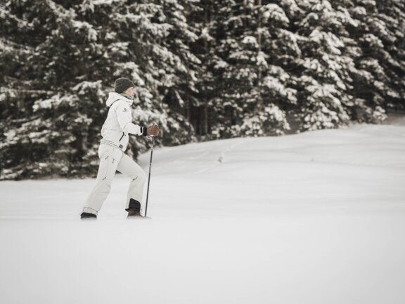 Person beim Schneeschuhwandern im Tannheimer Tal auf offener Stelle im Wald