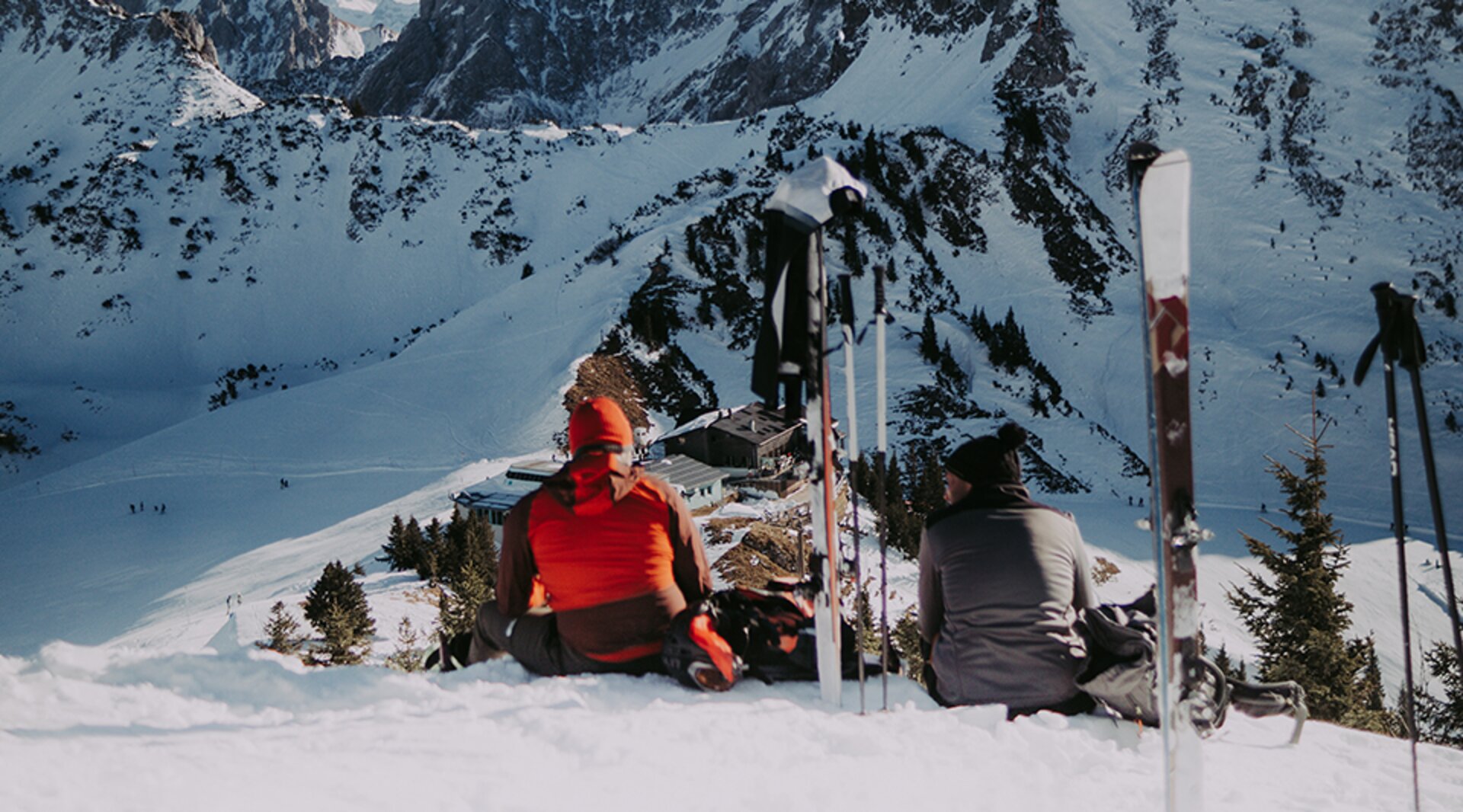 Skifahrer sitzen am Füssener Jöchle mit Blick auf die Skipiste