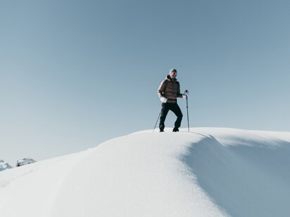 Person mit Schneeschuhen auf einem Gipfel im Winter im Tannheimer Tal