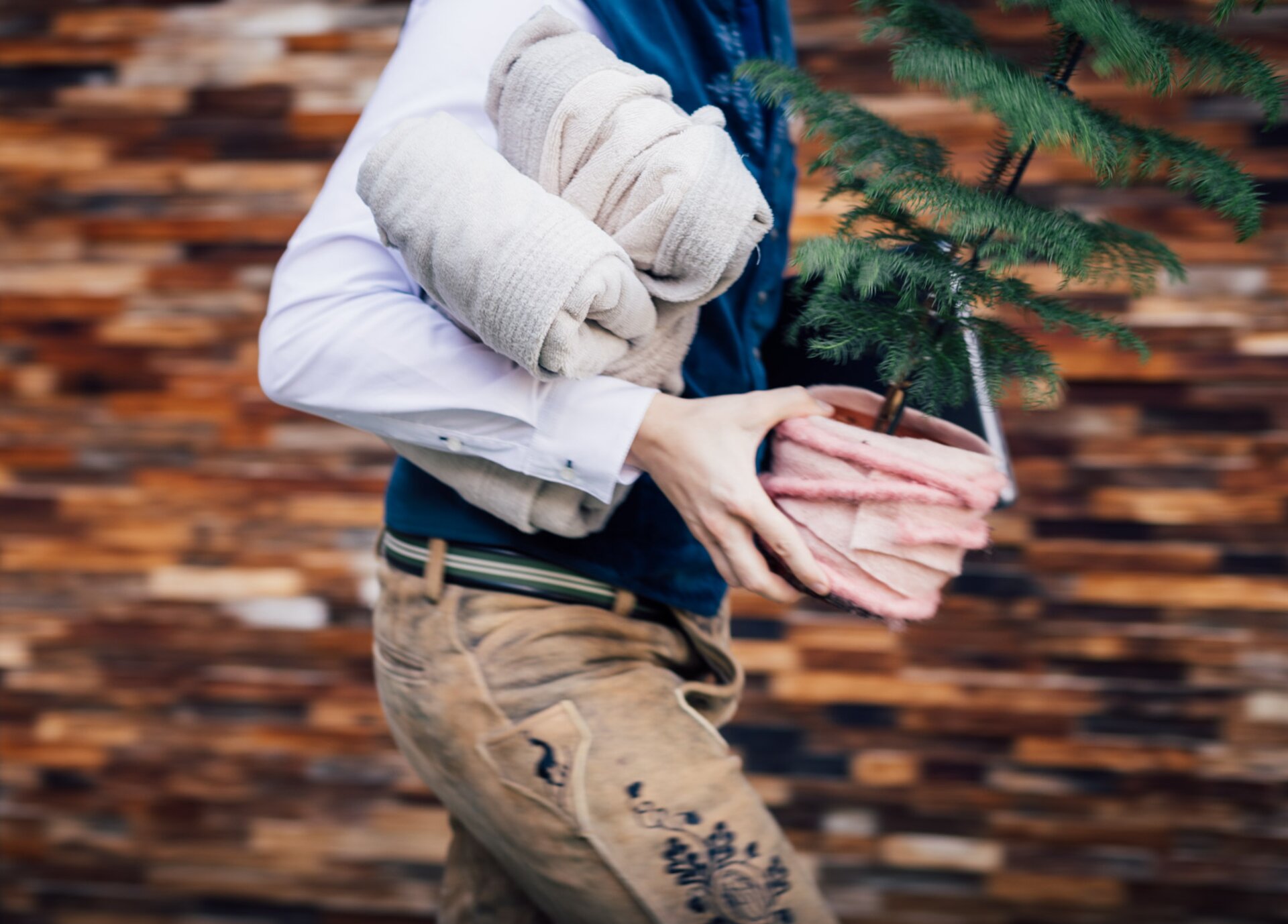 Person rennt im Vorweihnachtswahnsinn mit Bademänteln, Pflanze und Laptop in der Hand gestresst von A nach B