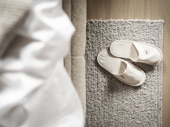 Orgänische Badeslipper auf Teppichboden neben Bett | Wellness-Kurzurlaub im Dezember 
