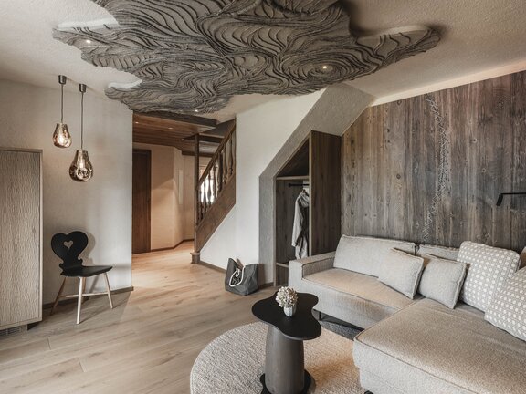 Orgänic Deluxe Suite "Häven" | Blick auf das Wohnzimmer mit Designercouch, Designlampe altem Stuhl Orgänic Deluxe Suite "Häven" | Blick auf das Wohnzimmer mit Designercouch, Designlampe altem Stuhl