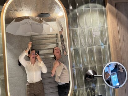 Clara mit Lichtschirm im Bad und Petra deckt die Lampe ab für das perfekte Licht am Foto