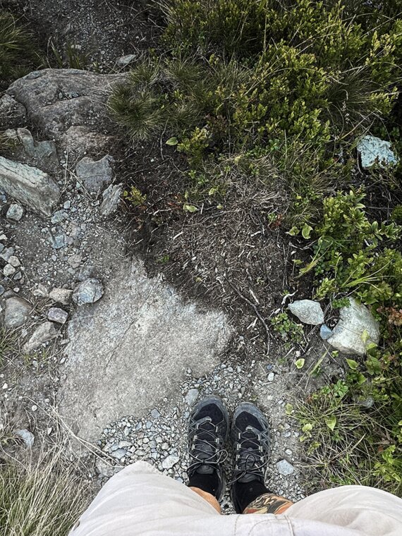 Aufnahme aus der Vogelperspektive auf die Füße einer Person die beim Wandern in den Allgäuer Alpen ist