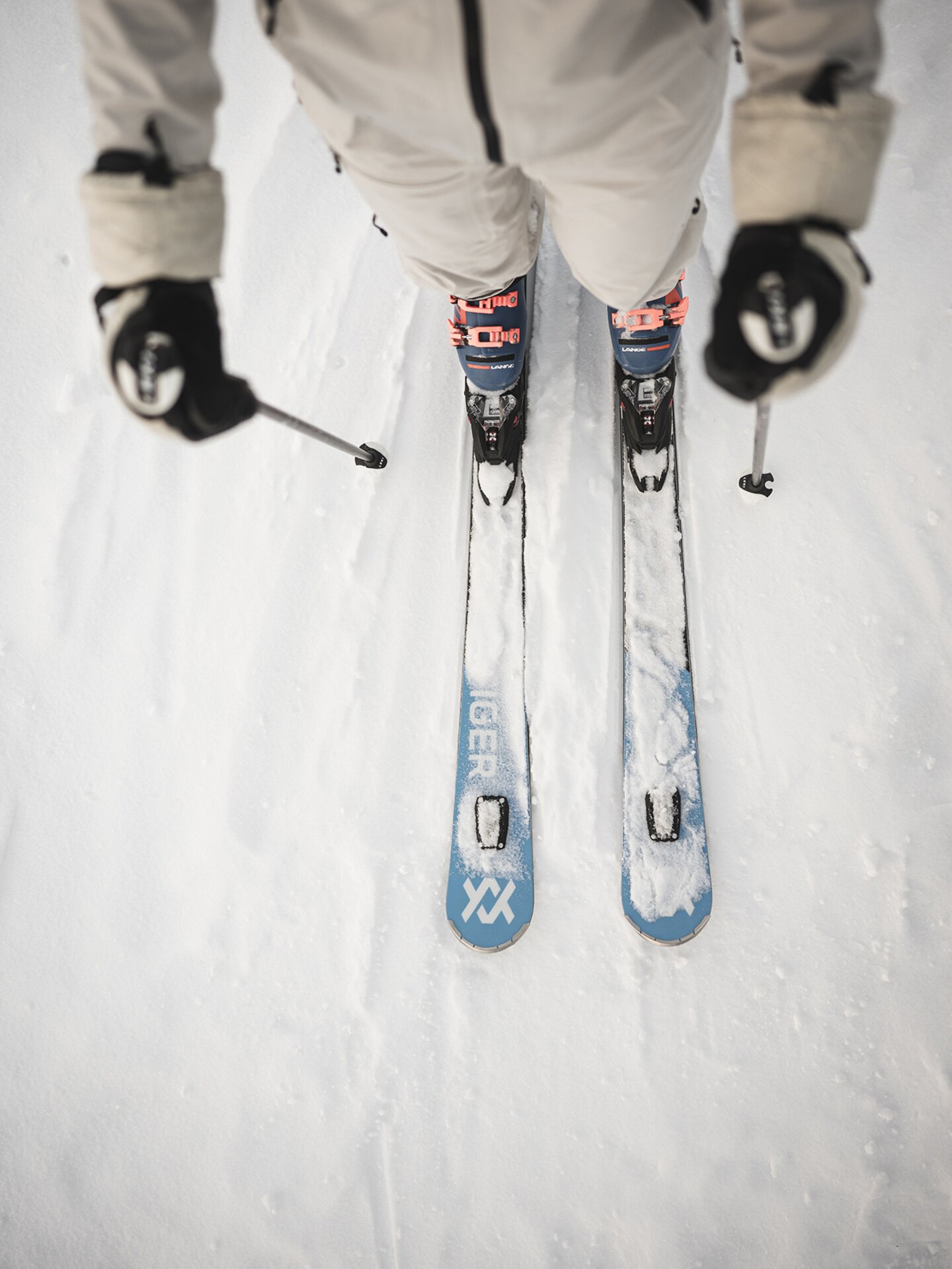 Person mit beigem Salewa-Skianzug und blauen Völkel-Ski in Vogelperspektive