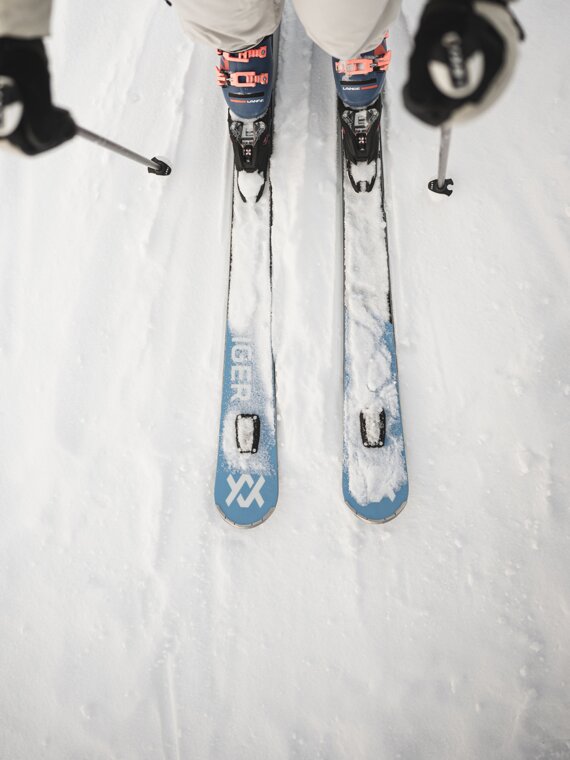 Person mit beigem Salewa-Skianzug und blauen Völkel-Ski in Vogelperspektive