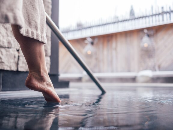 Wellnessgast tippt mit Zehenspitzen in den Kaltwasserpool im Wellnesshotel Der Engel