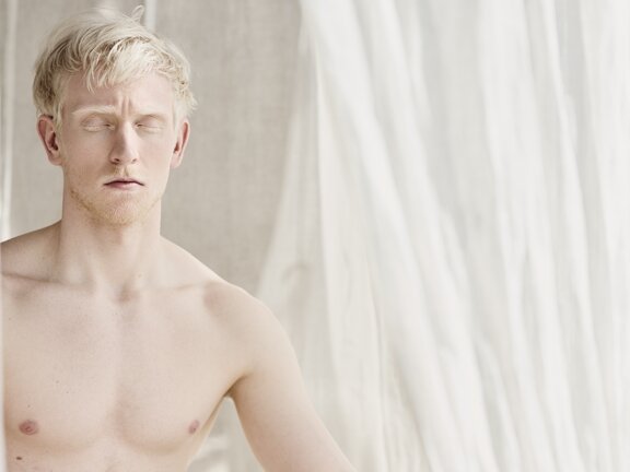 Person sitzend beim Meditieren hinter weißem Vorhang im Orgänic Spa | Wellnesshotel Der Engel